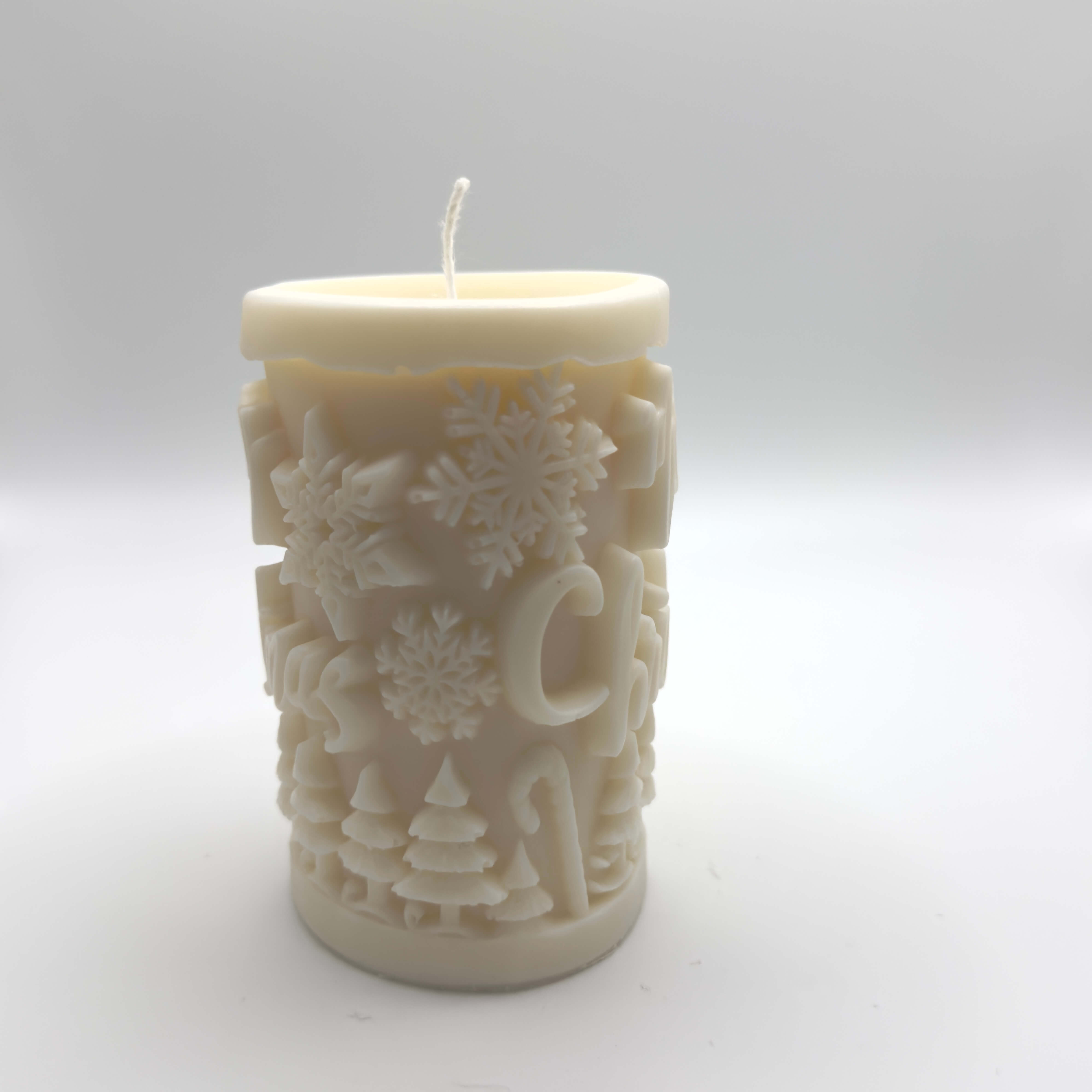 Winter Forest Sojawachs-Kerze in Baumstammform mit “Merry Christmas” und winterlichen Motiven wie Tannen und Schneeflocken.