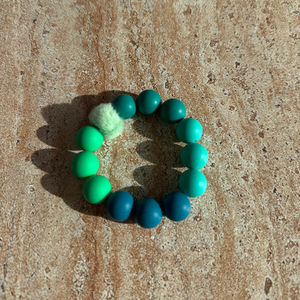 „Aqua Breeze Armband in Blau und Türkis auf einem Tisch liegend, Sym Aesthetics.“