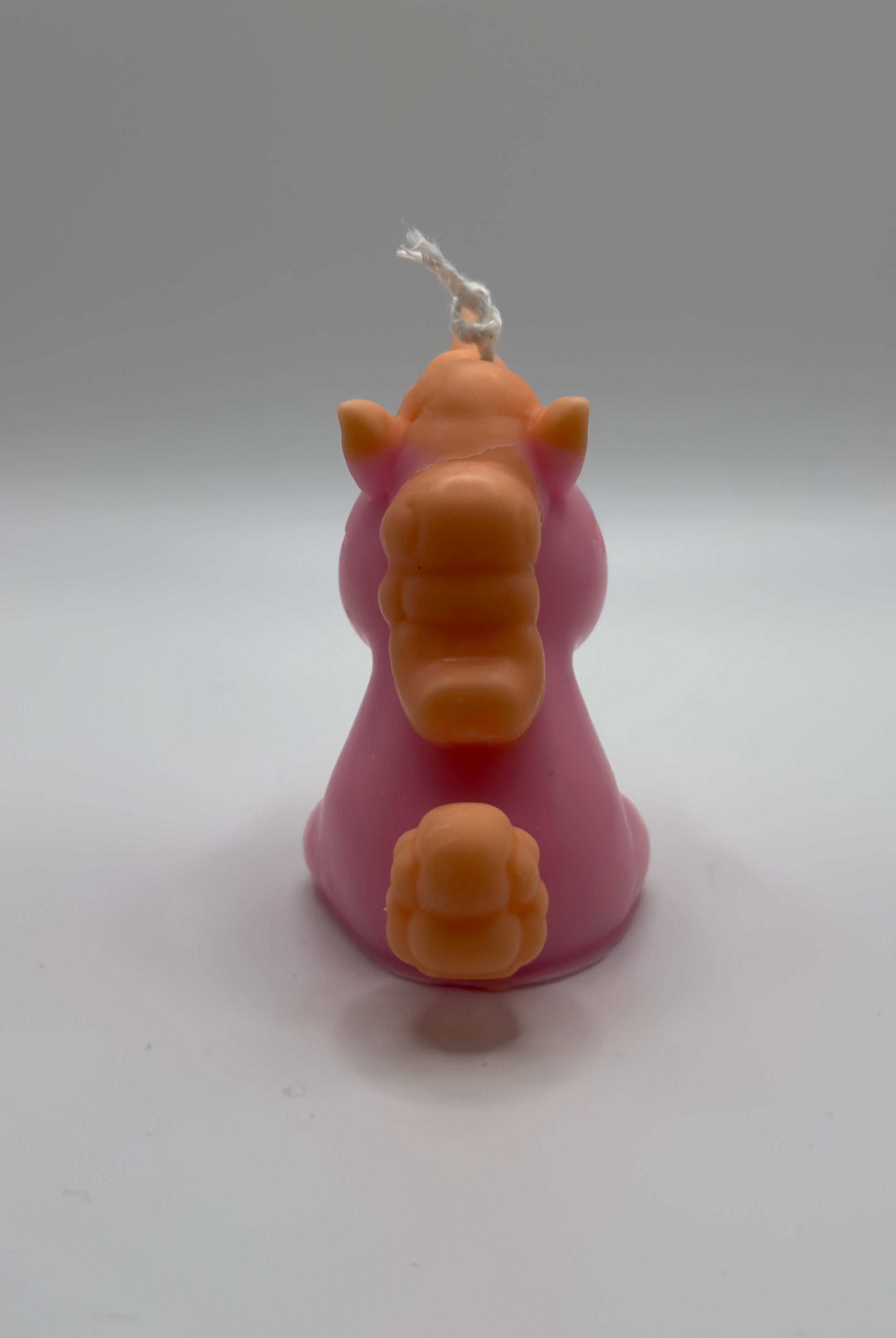 Handgemachte Celestial Unicorn Einhornkerze aus Sojawachs in Rosa mit orangefarbener Mähne, Schweif und Horn – nachhaltige Dekokerze im Fantasy-Design.