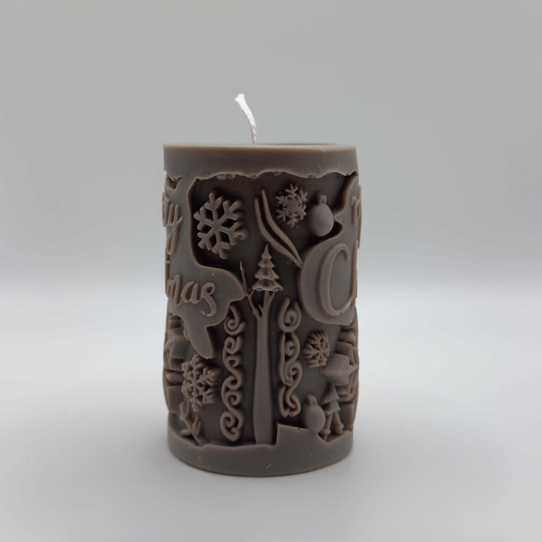 Die „Snowy Cheer“ Kerze in Dunkelbraun bringt mit ihrem charmanten Baumstamm-Design, Schneeflocken und festlichem Schriftzug eine gemütliche Atmosphäre in dein Zuhause.