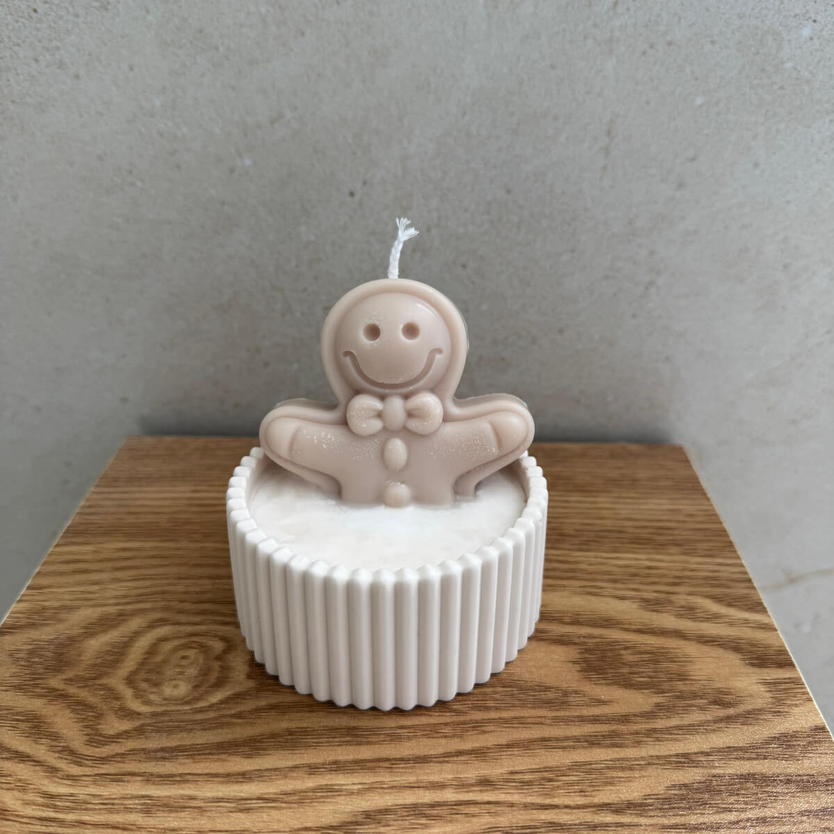 Nahaufnahme der Gingerbread Bath Kerze mit Wachs-Lebkuchenmännchen, Schokoladenstücken und winterlicher Candy-Deko.