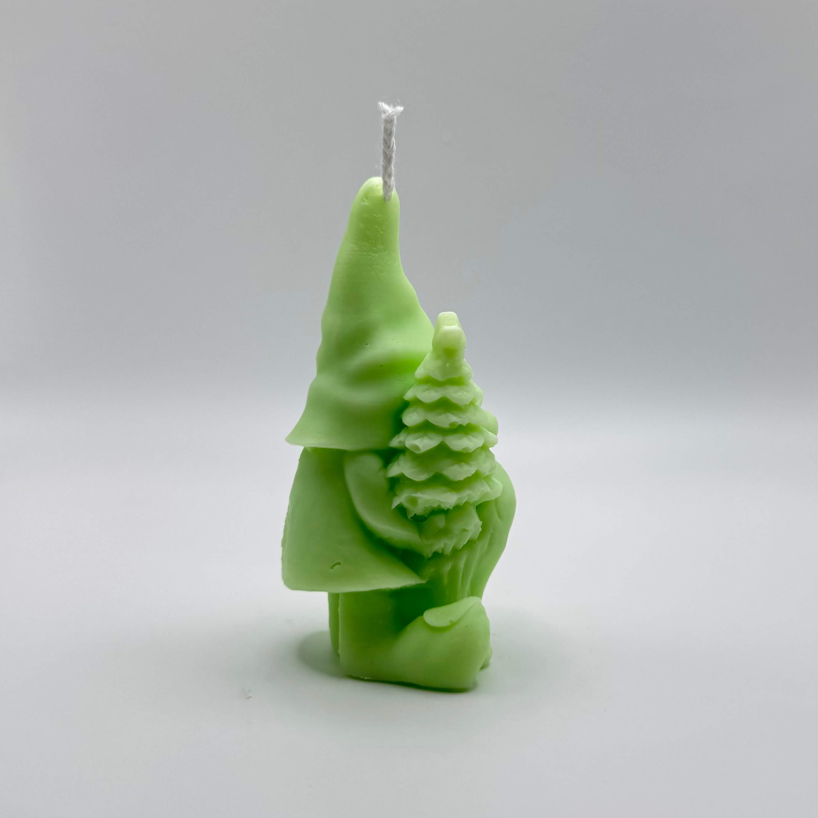 Verspielte “Gnome’s Gift”-Kerze in grün. Der Wichtel mit Baum und Geschenk sorgt für festliche Weihnachtsfreude.