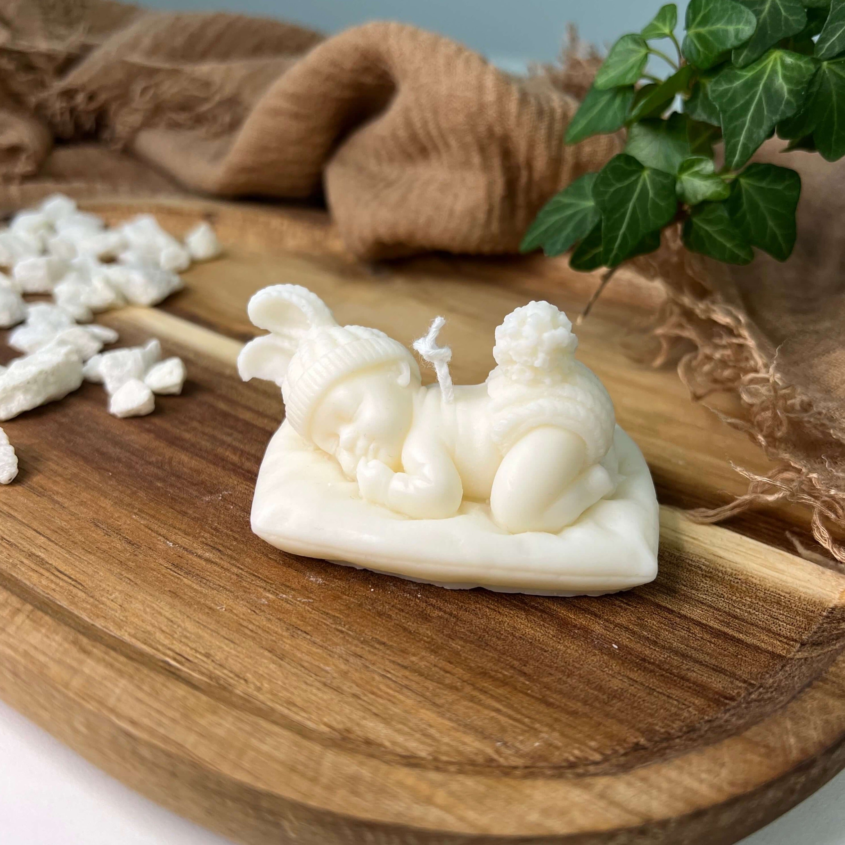 Die handgemachte und vegane Sojawachskerze Heavenly Slumber Bunny. Sie zeigt ein schlafendes Baby mit Hasenohren, liegend auf einem Kissen.