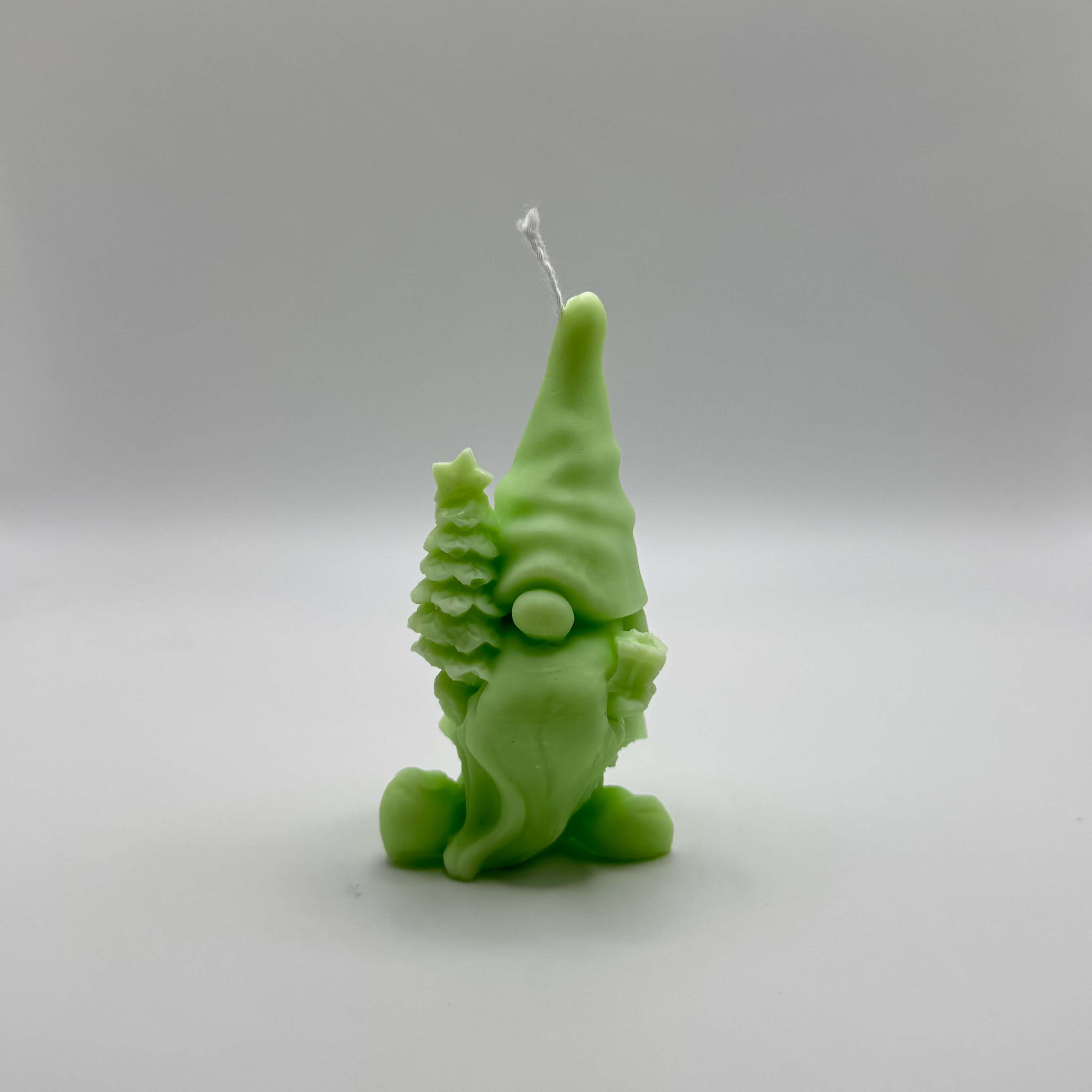 Hellgrüne “Gnome’s Gift”-Kerze aus handgefertigtem Sojawachs. Ein niedlicher Wichtel mit Tannenbaum und Geschenk. Perfekt für nachhaltige Weihnachtsdeko.