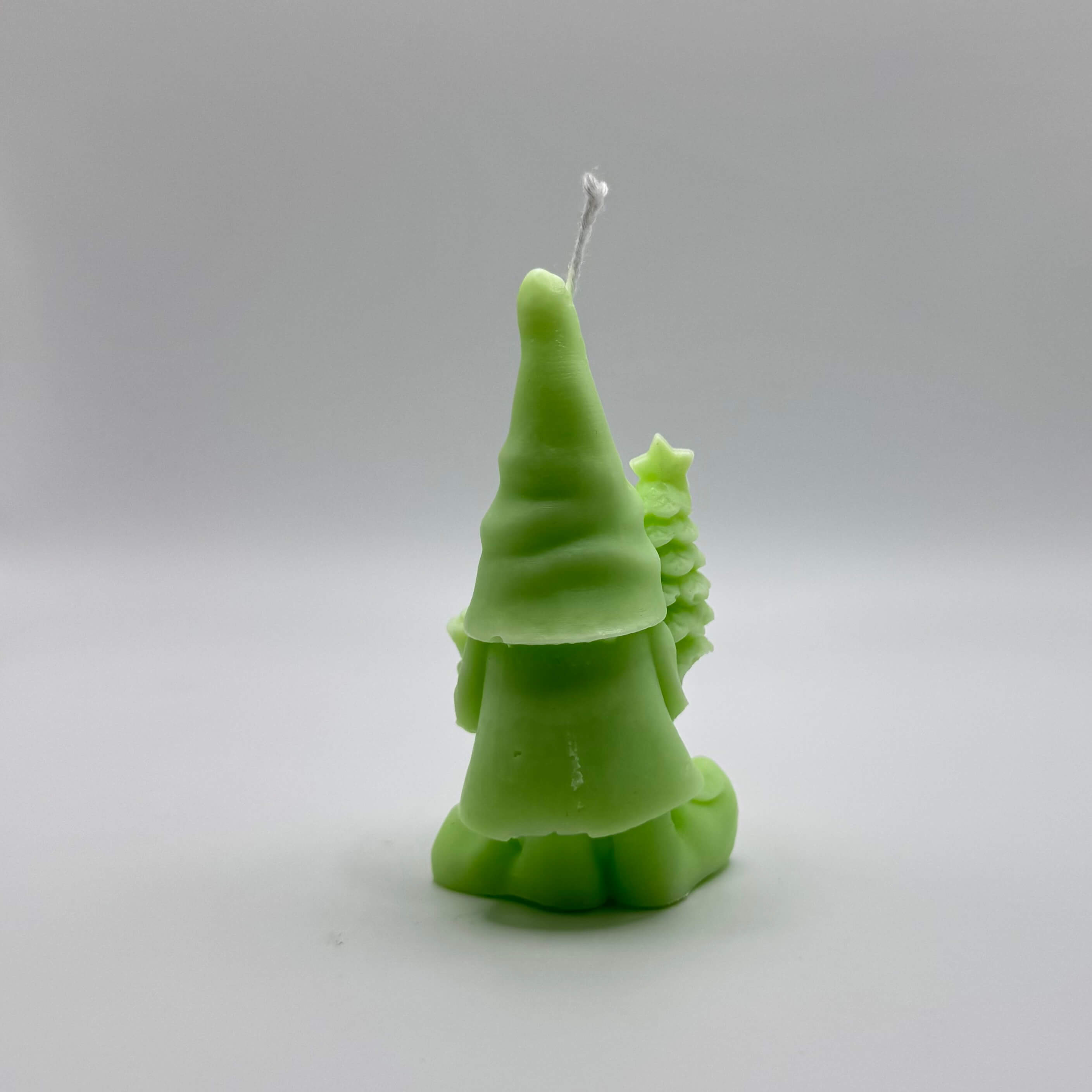 Handgefertigte Wichtel-Kerze in hellgrünem Sojawachs. Mit Tannenbaum und Geschenk als liebevolle Details.