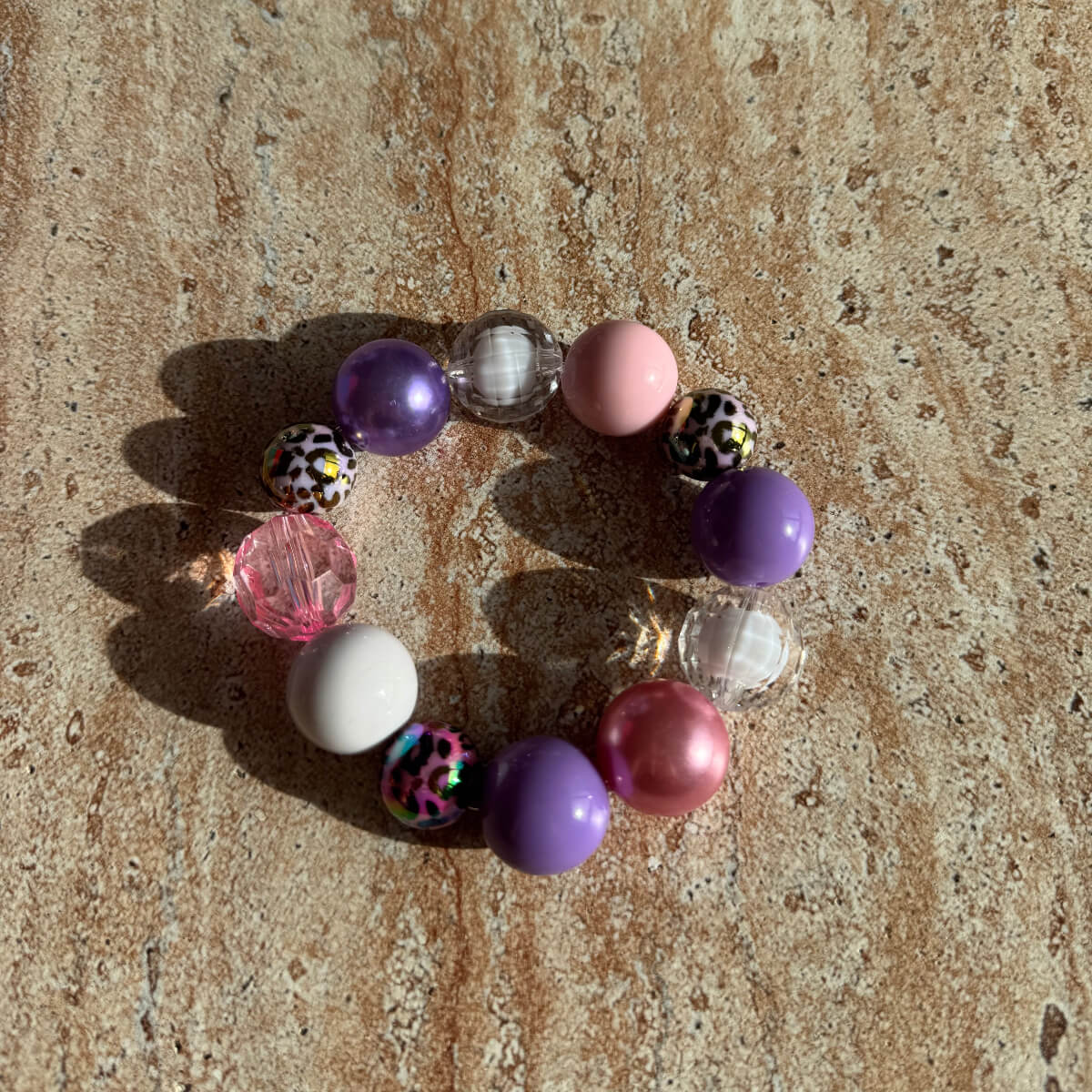 Armband Pastel Safari auf einem Tisch in natürlichem Licht, mit pastellfarbenen und Leopard-Beads.