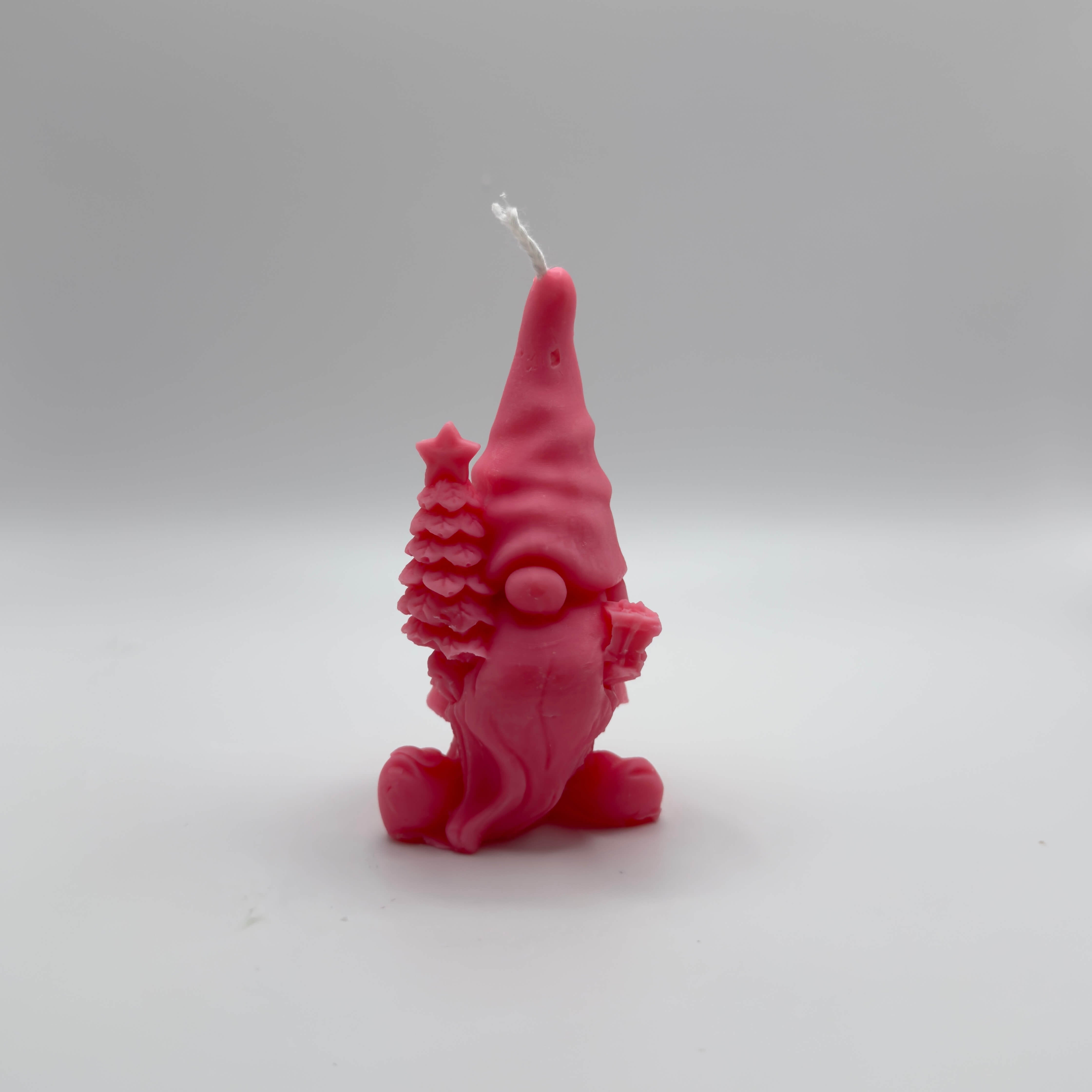 Handgefertigte pinke “Gnome’s Gift”-Kerze aus Sojawachs. Der Wichtel hält einen Baum und ein Geschenk. Perfekt für Weihnachtsdeko.