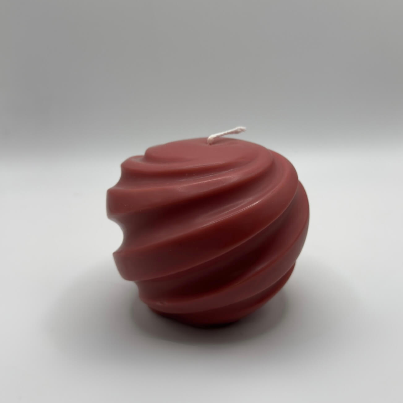 Die handgefertigte „Ribbed Christmas Bauble“ Kerze in Rot beeindruckt mit ihrer eleganten Kugelform und den einzigartigen Spiralrillen. Perfekt für eine stilvolle Weihnachtsdekoration.