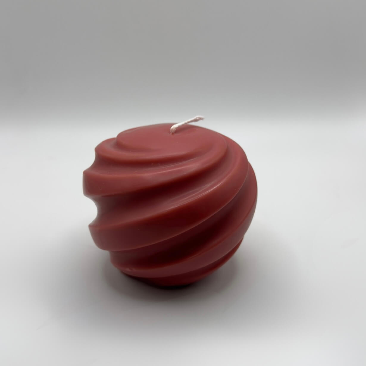 Die handgefertigte „Ribbed Christmas Bauble“ Kerze in Rot, gefertigt aus umweltfreundlichem Sojawachs, beeindruckt mit ihrer eleganten Kugelform und einzigartigen Spiralstruktur. Perfekt für festliche Dekorationen.