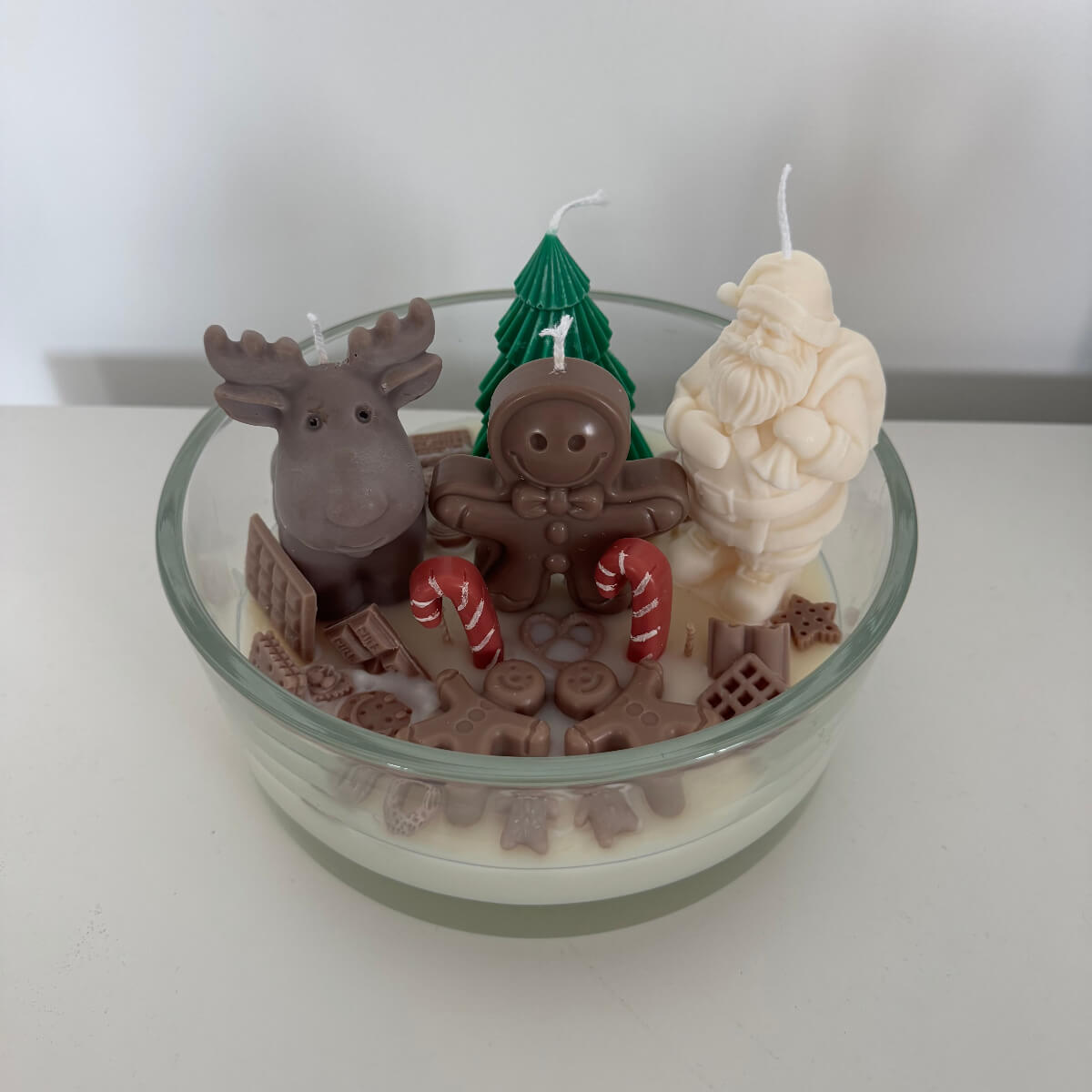 Santa’s Sweet Wonderland Kerze von der Seite, mit sichtbarem Lebkuchenmann, Elch und winterlichem Wachsboden.