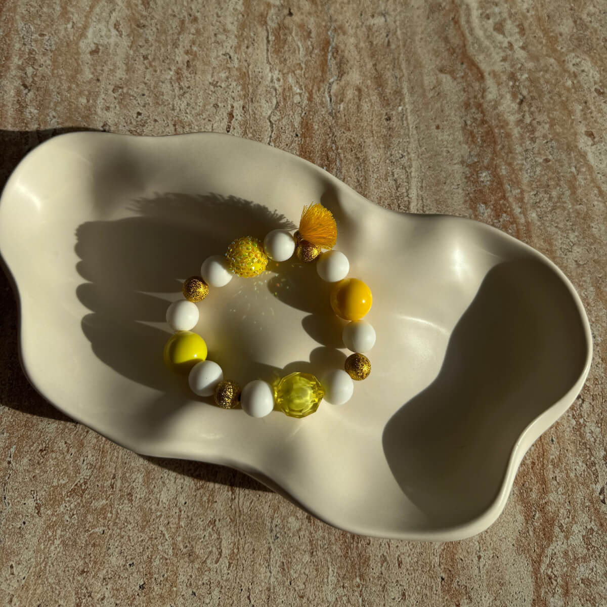 Komplettes Sunny-Sorbet-Armband in einer dekorativen Schale, sommerliche Gelb- und Weißperlen.