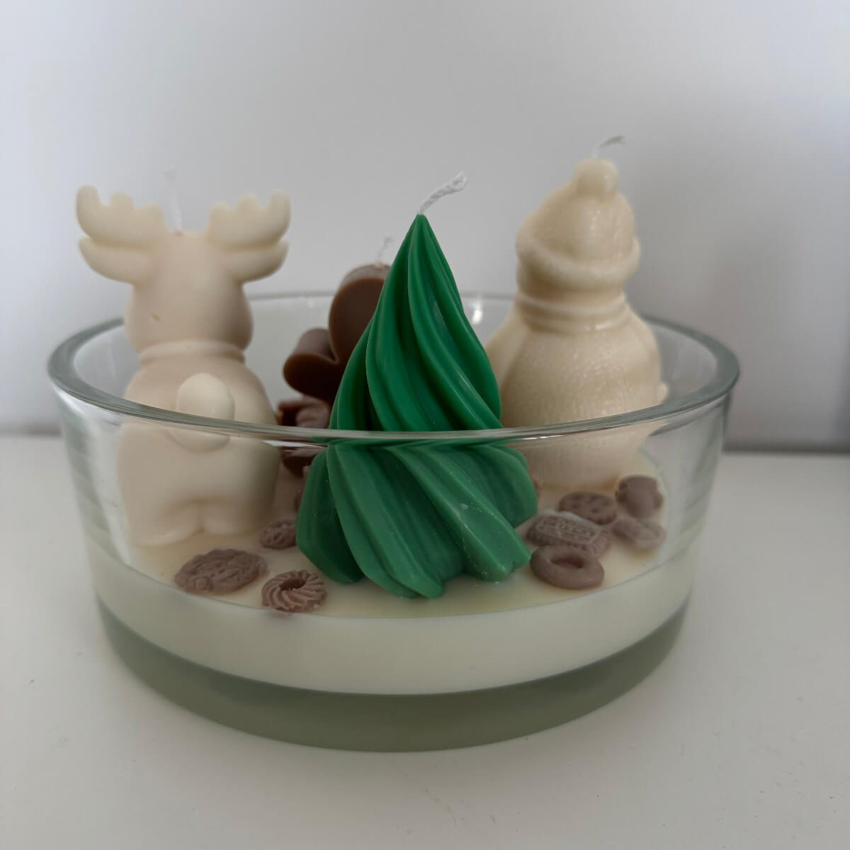 Detailansicht der Miniaturdekoration aus Wachs mit Schokolade, Süßigkeiten und winterlichen Figuren auf weißem Wachs.