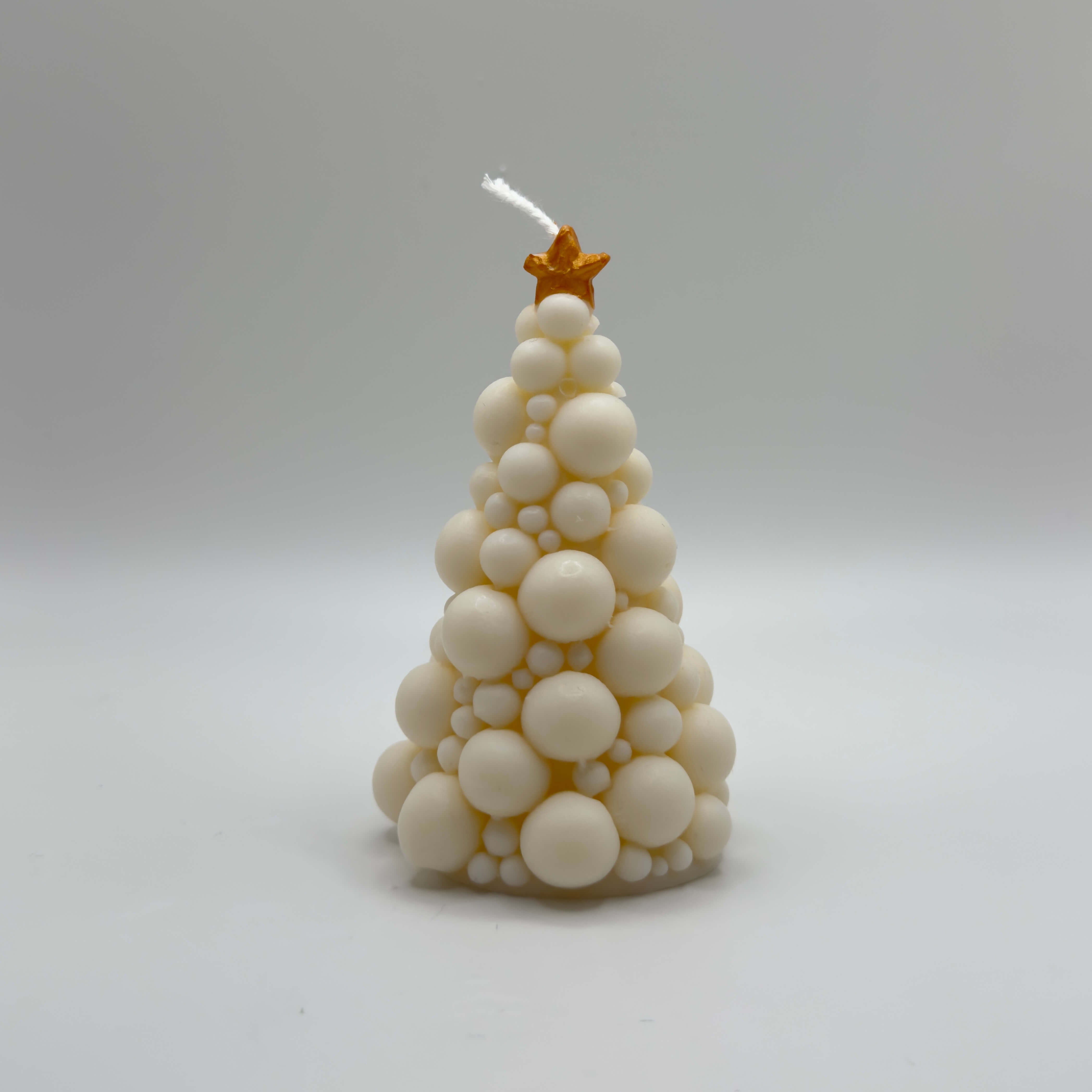 Die “Bubbly Christmas Tree Candle” in Weiß mit goldenem Stern. Diese handgefertigte Sojawachs-Kerze besticht durch ihr modernes Bubble-Design und ihren funkelnden Stern, ideal für stilvolle Weihnachtsdekorationen.