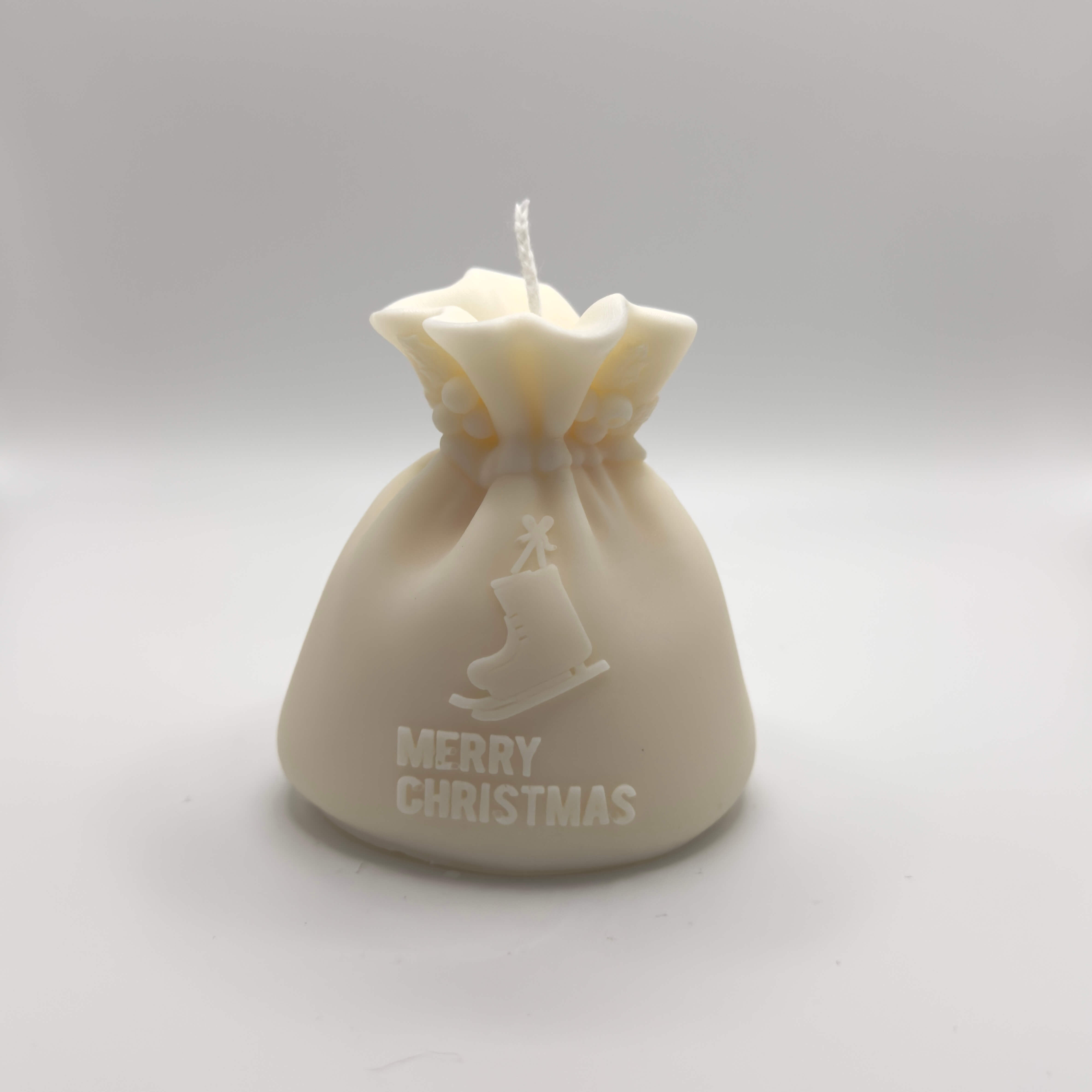 Santa’s Gift handgefertigte Sojawachs-Kerze, gestaltet wie ein Geschenk, mit Schlittschuhmotiv und “Merry Christmas”-Schriftzug.