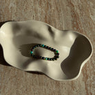 Komplettes Perlenarmband in changierenden Farben, dekorativ in einer Schale präsentiert.