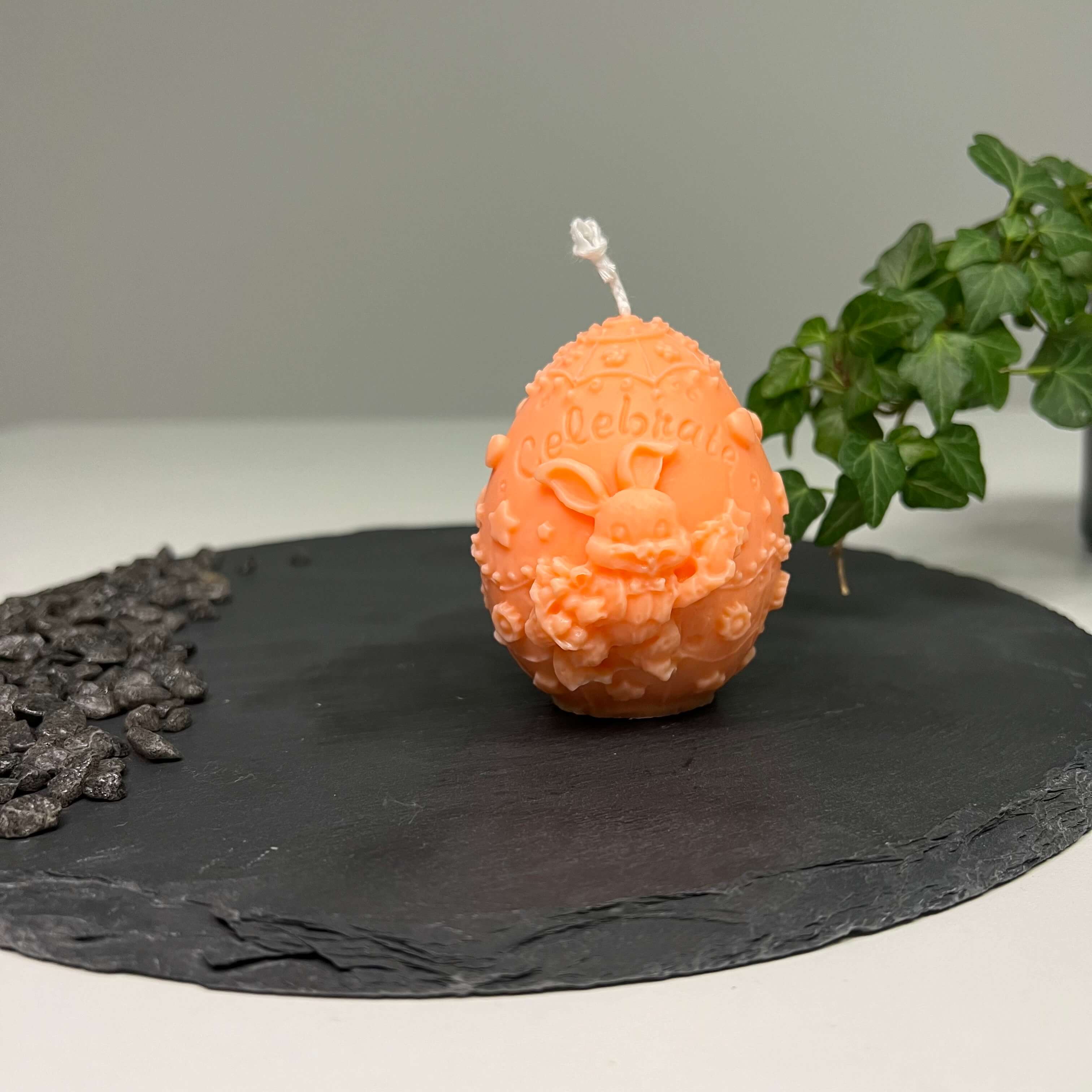 Auf diesem Bild sieht man unsere Bunny Celebration Egg Kerze. Sie ist handgemacht aus Sojawachs. Zudem ist sie auch nachhaltig, vegan und umweltfreundlich. In orange.
