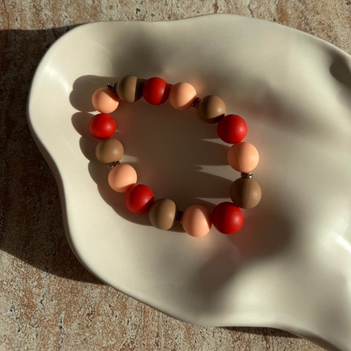 Nahaufnahme des Caramel Ember Armbands in einer Schale mit warmem Licht.