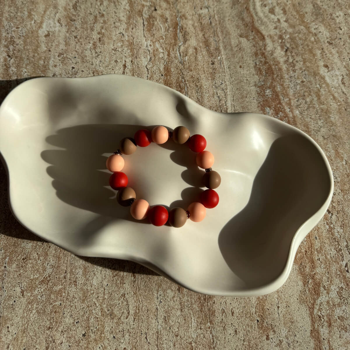 Komplettes Caramel Ember Armband in einer cremefarbenen Schale, warmes Farbspiel.