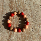 Armband Caramel Ember aus roten, nude und caramel-farbenen Perlen – fotografiert auf einem Tisch.