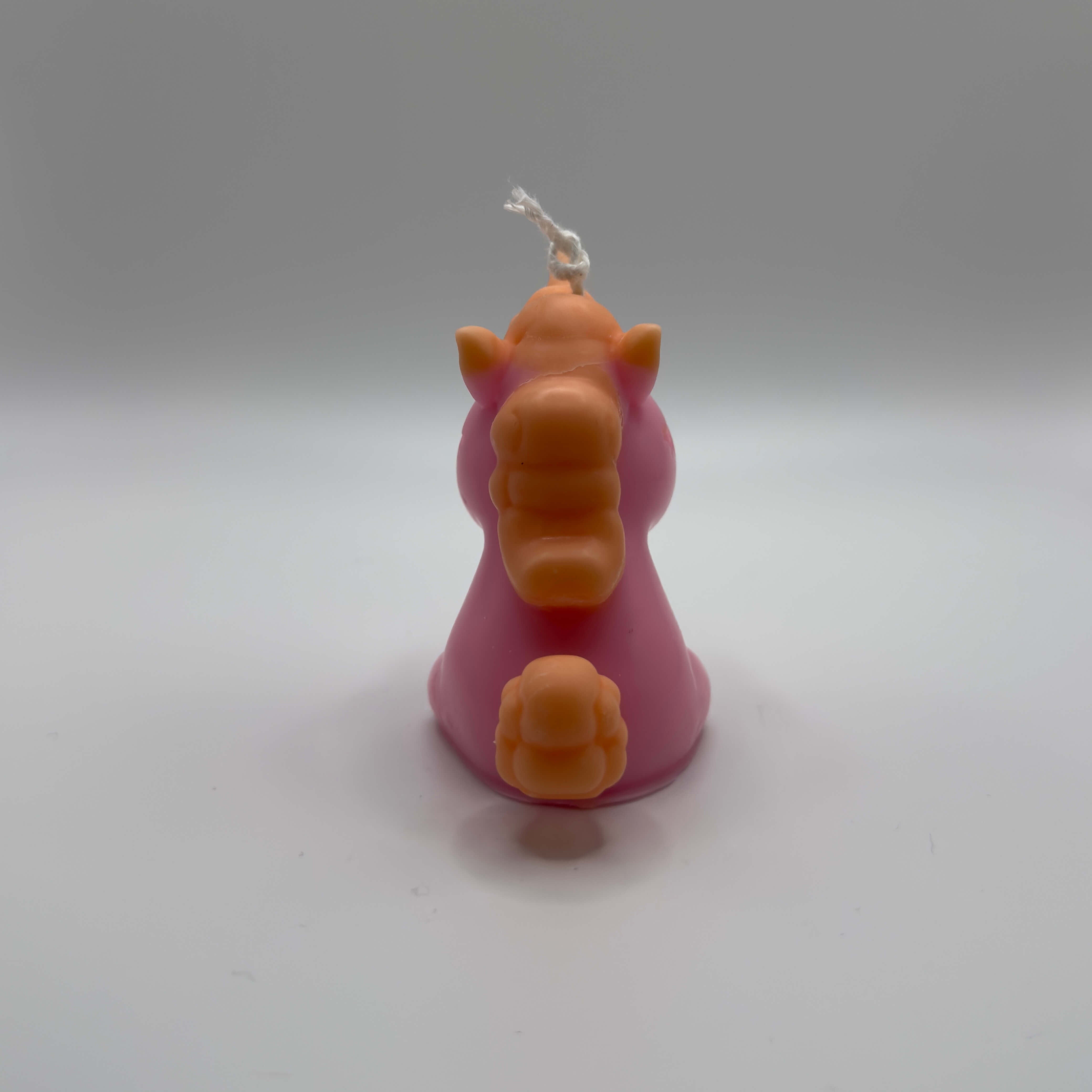 Handgemachte Celestial Unicorn Einhornkerze aus Sojawachs in Rosa mit orangefarbener Mähne, Schweif und Horn – nachhaltige Dekokerze im Fantasy-Design.