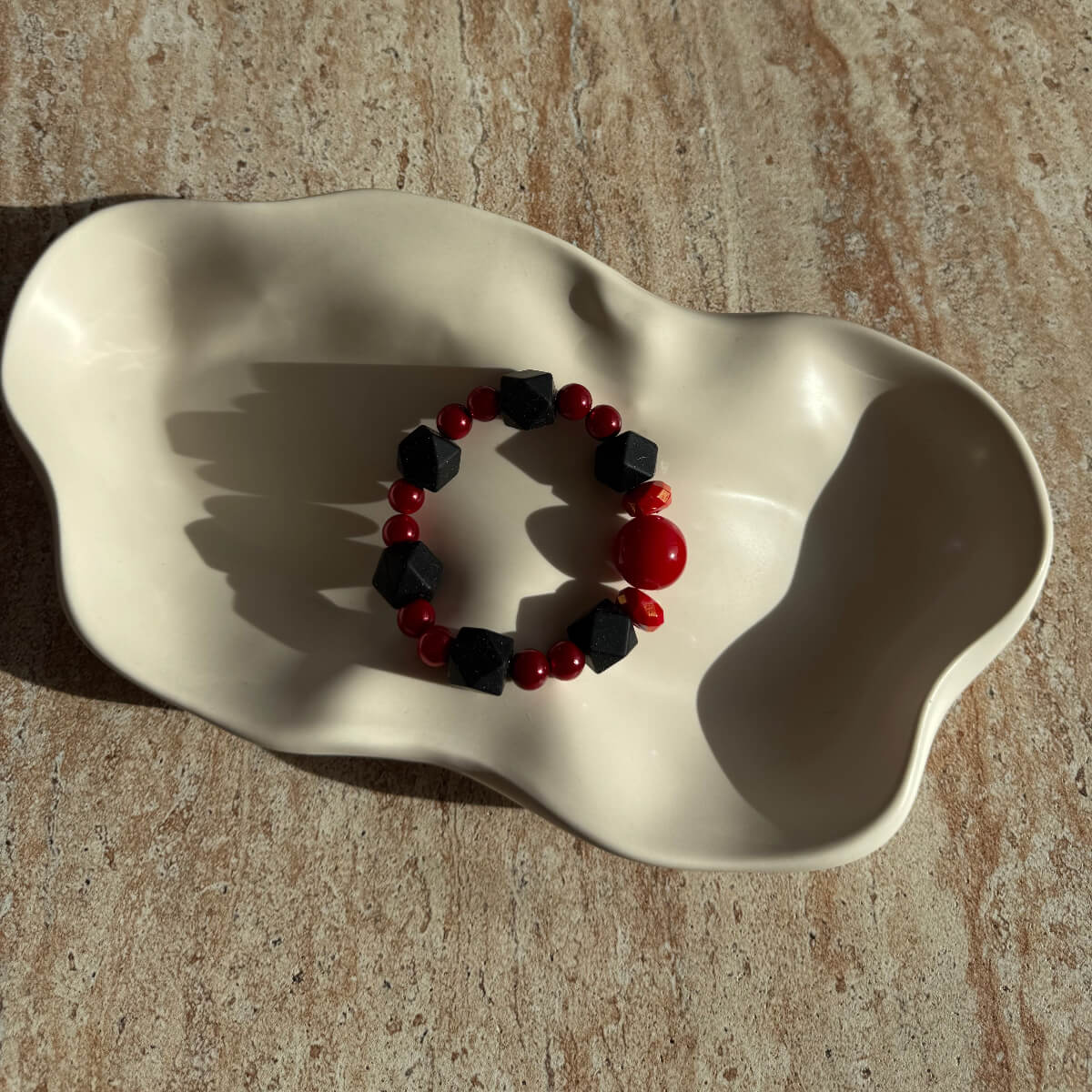 Komplettes Crimson Shadows Armband in der Schale, mit Fokus auf den Farbkontrast von Schwarz und Rot.