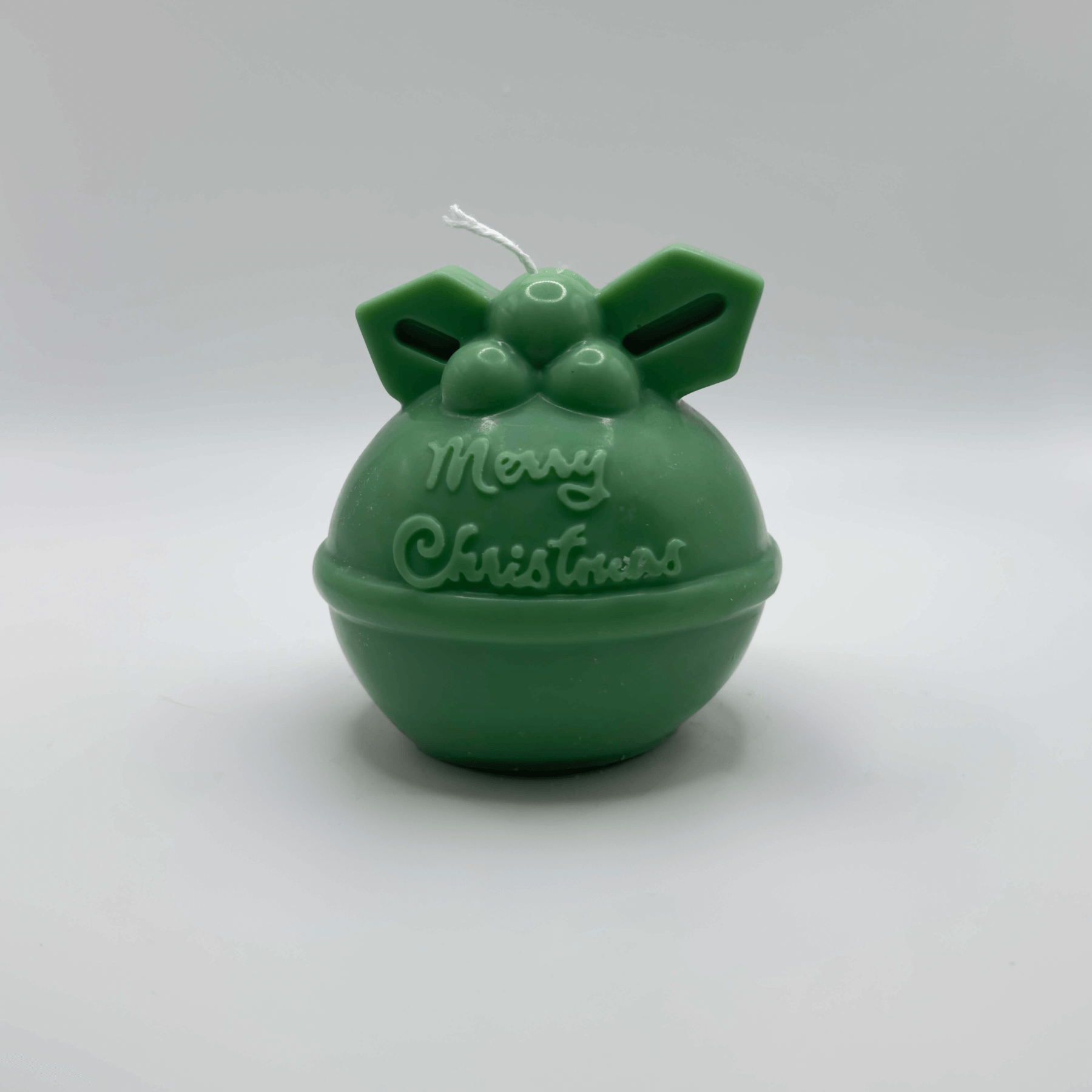 Die „Mistletoe Merry“-Kerze in Dunkelgrün mit ihrem klassischen Kugeldesign, einem filigranen Mistelzweig und dem Schriftzug „Merry Christmas“ ist ein festlicher Blickfang aus umweltfreundlichem Sojawachs.