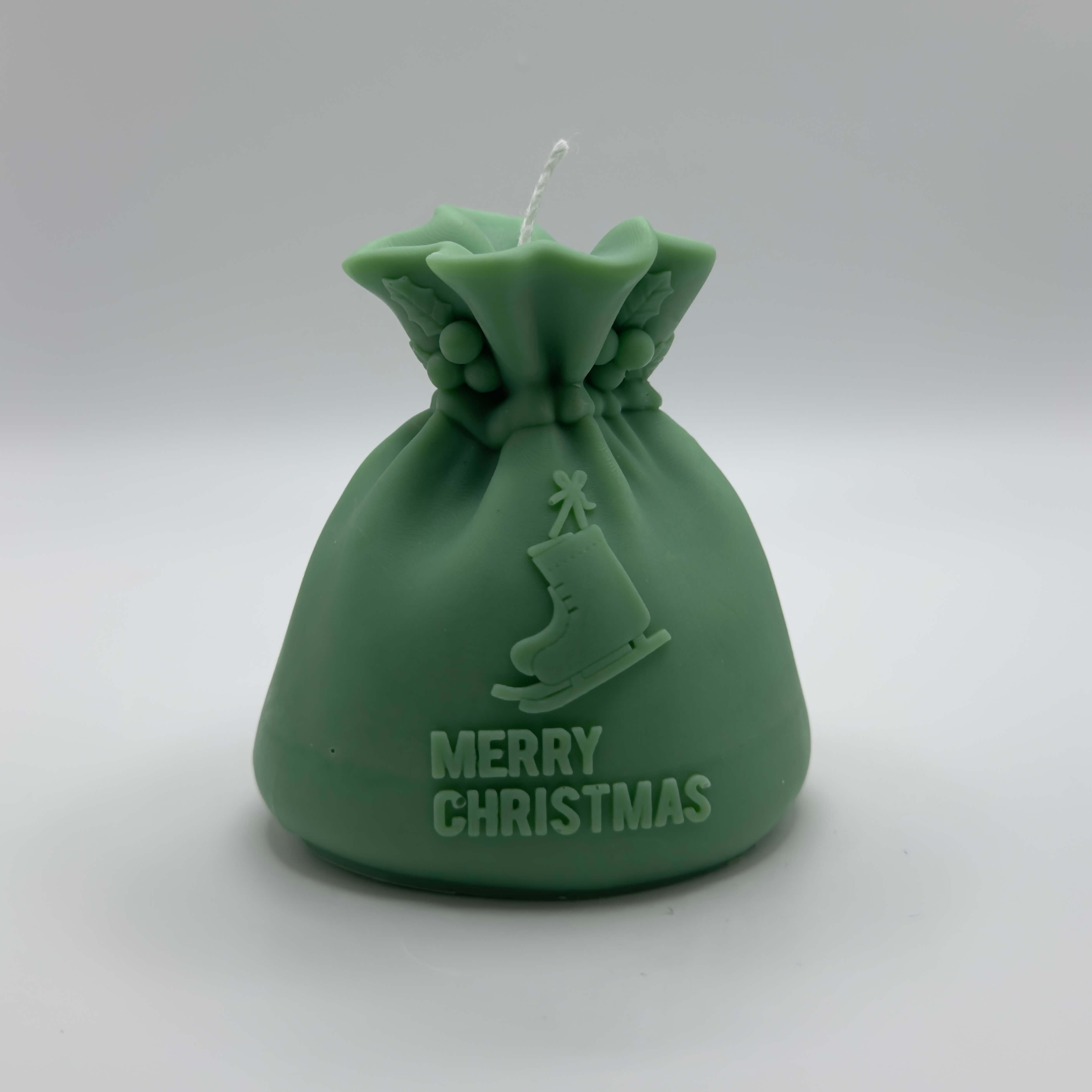 Dunkelgrüne “Santa’s Gift Candle” aus handgefertigtem Sojawachs. Ein weihnachtliches Design mit Schlittschuh und “Merry Christmas”-Schriftzug.
