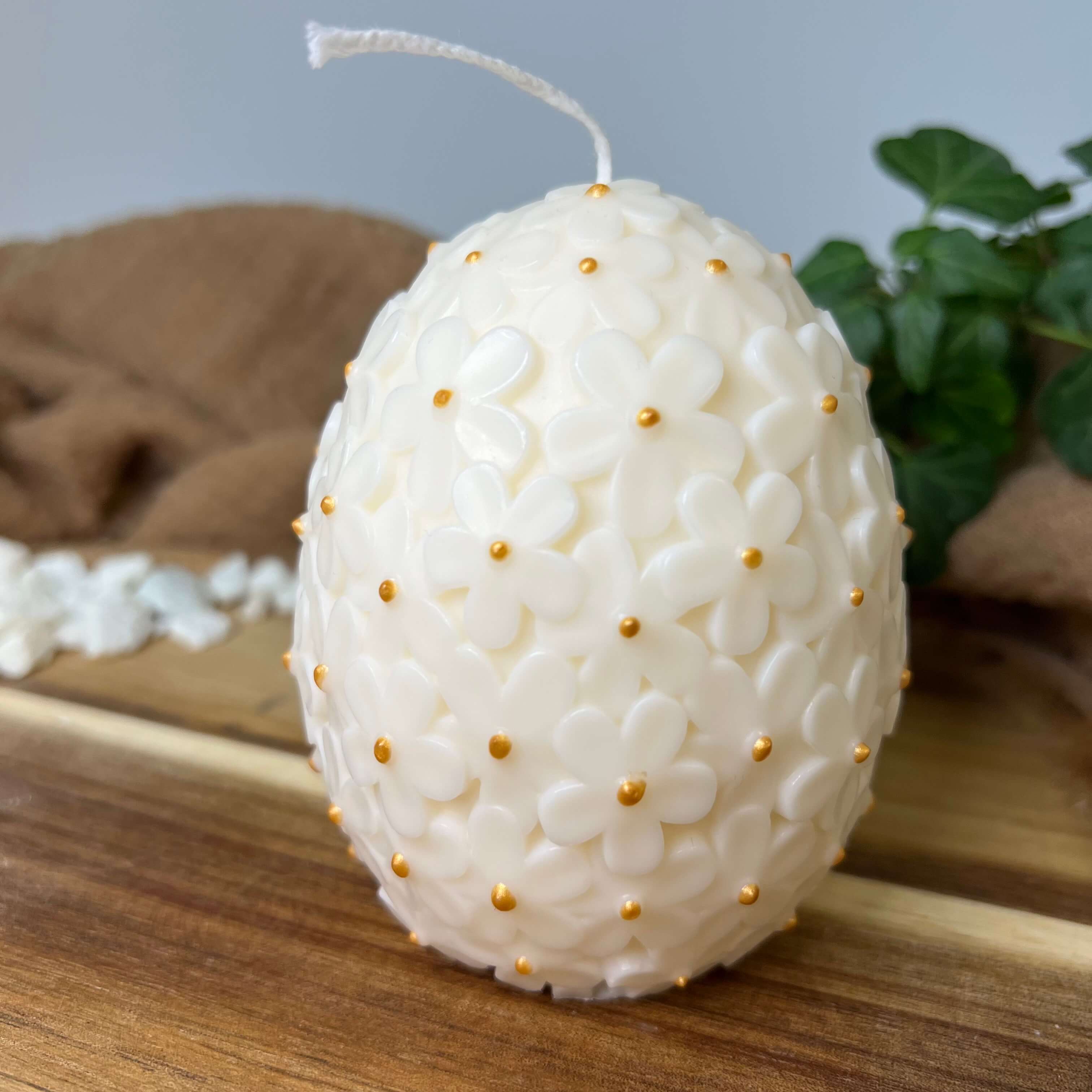 Auf diesem Bild sieht man unsere Floral Easter Egg Brilliance Kerze. Sie ist handgemacht aus Sojawachs. Sie ist nachhaltig, vegan und umweltfreundlich. In Weiß-Gold.