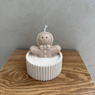 Nahaufnahme der Gingerbread Bath Kerze mit Wachs-Lebkuchenmännchen, Schokoladenstücken und winterlicher Candy-Deko.