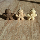 „Drei Gingerbread-Kerzen in verschiedenen Farben auf einem Tisch – Sym Aesthetics.“