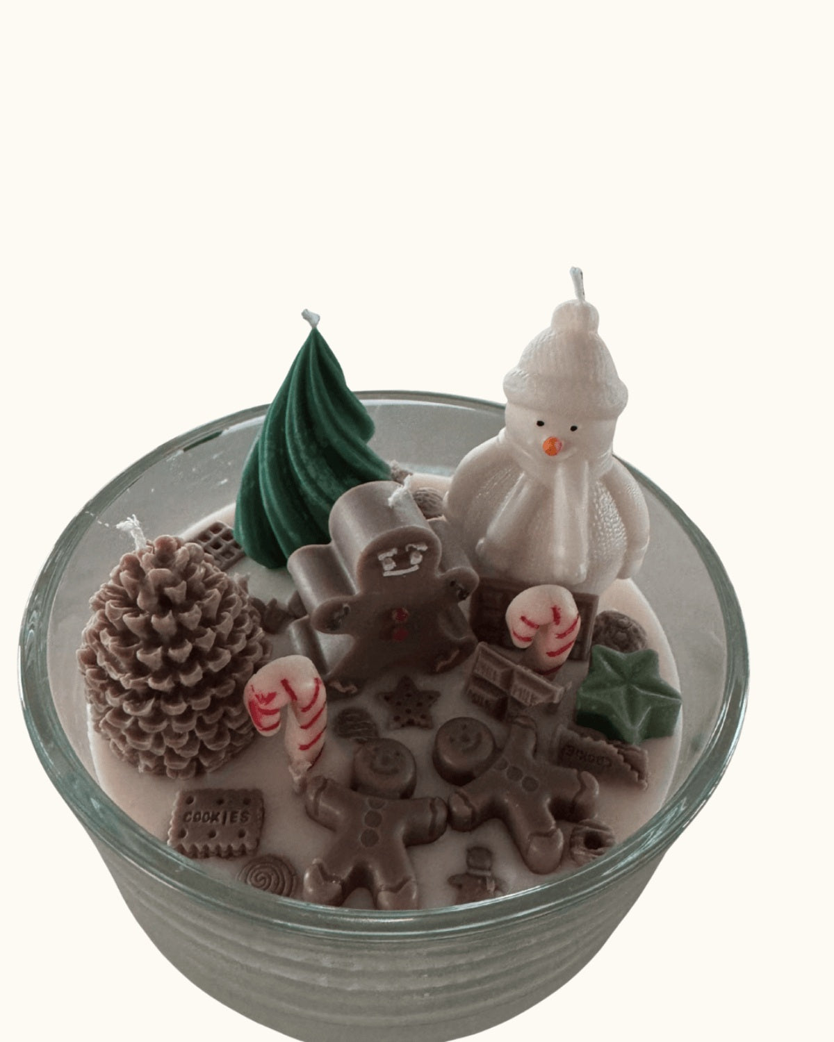 Handgegossene Weihnachtskerze in runder Schale auf einem Holztisch, mit schneeweißem Wachsboden und süßen Candy-Deko-Elementen inspiriert von Hänsel und Gretel.