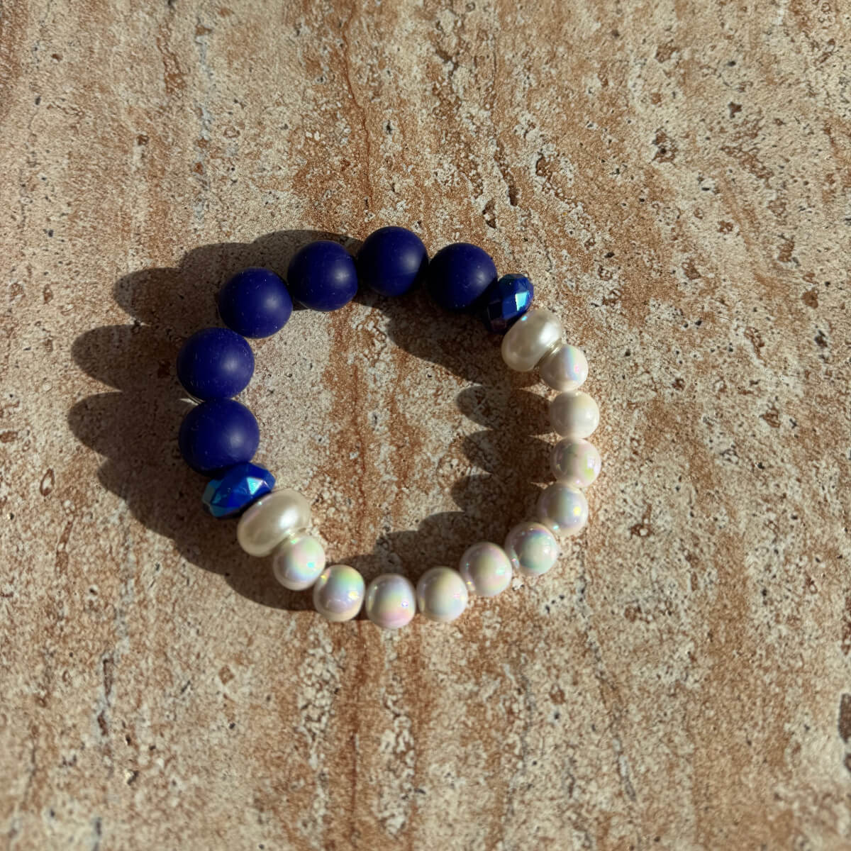 Armband Lunar Sapphire auf einem Tisch in natürlichem Licht, mit blauen und weißen Perlen.