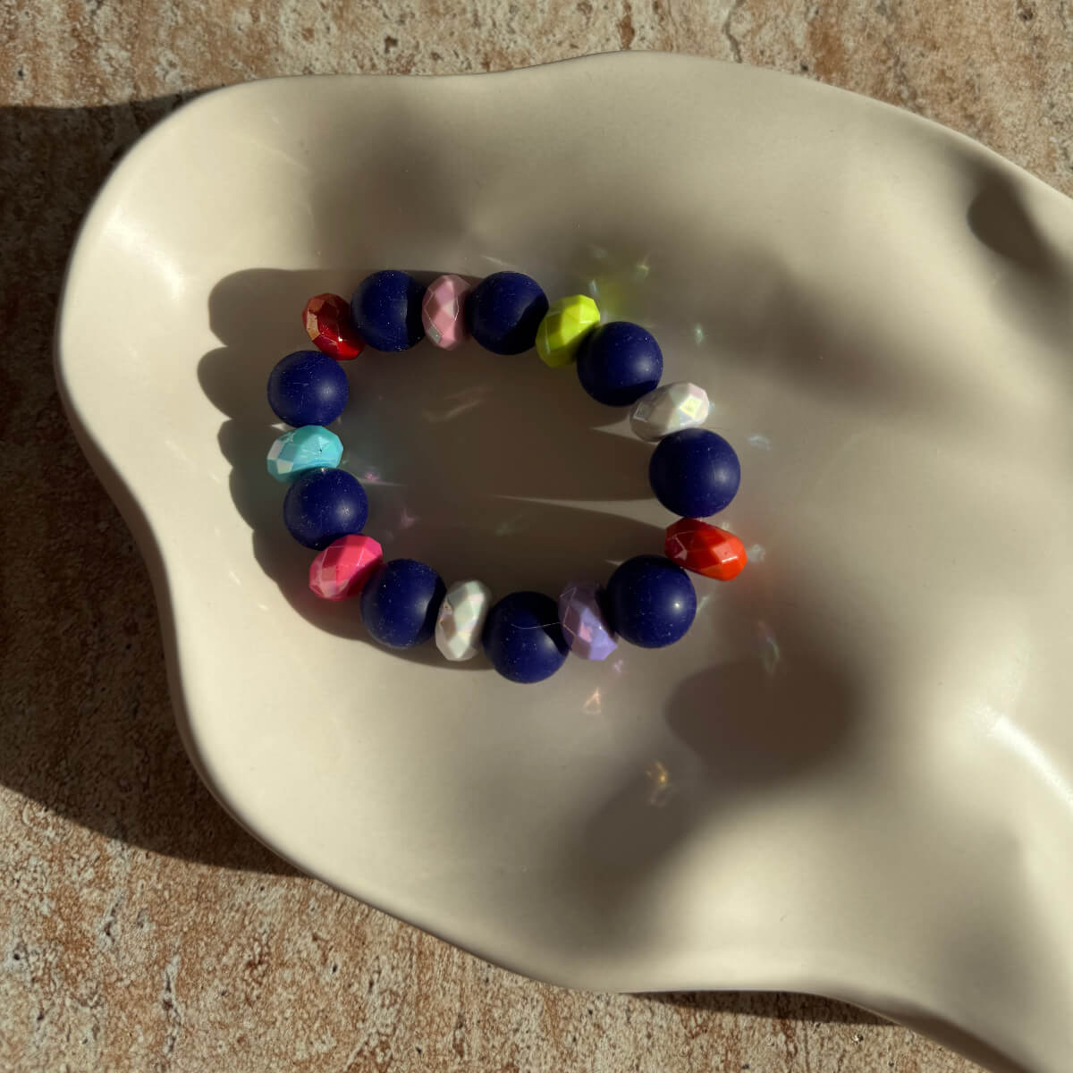 Nahaufnahme des Midnight Carnival Armbands in der Schale mit farbigen Akzentperlen.