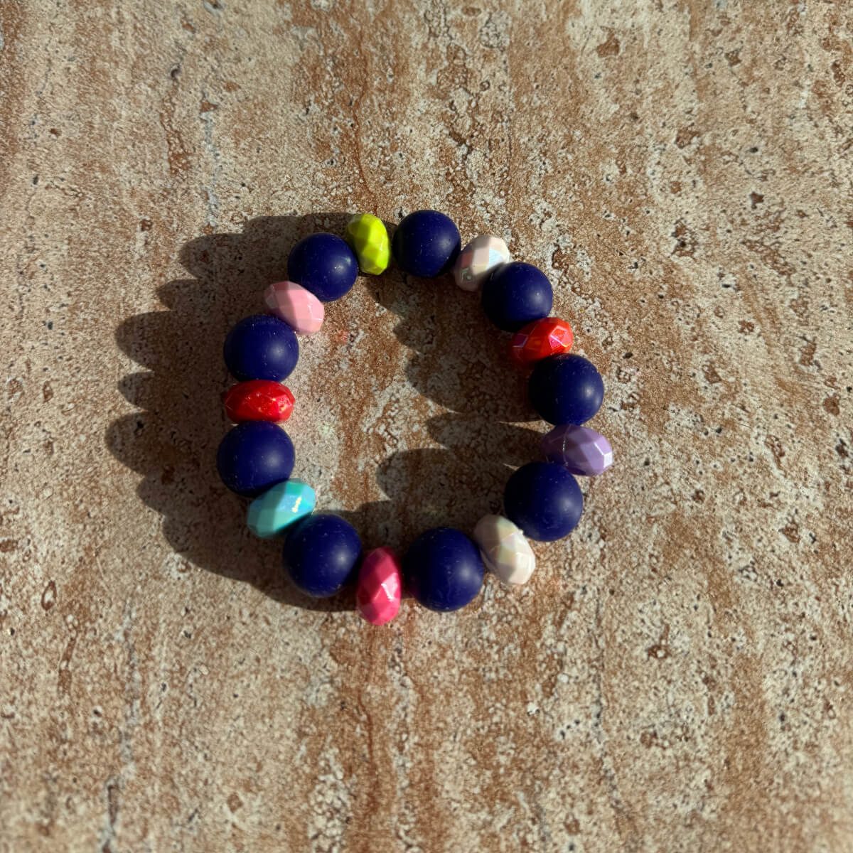 Armband Midnight Carnival auf dem Tisch mit dunkelblauen und bunten Perlen.