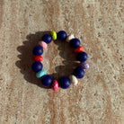 Armband Midnight Carnival auf dem Tisch mit dunkelblauen und bunten Perlen.