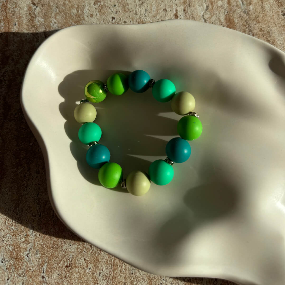 Nahaufnahme des Minty Ocean Breeze Armbands in einer Schale, Fokus auf den bunten Perlen