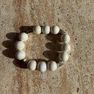 Pearl Whisper Armband auf einem Tisch, weiße schimmernde Perlen mit Herzdetails.