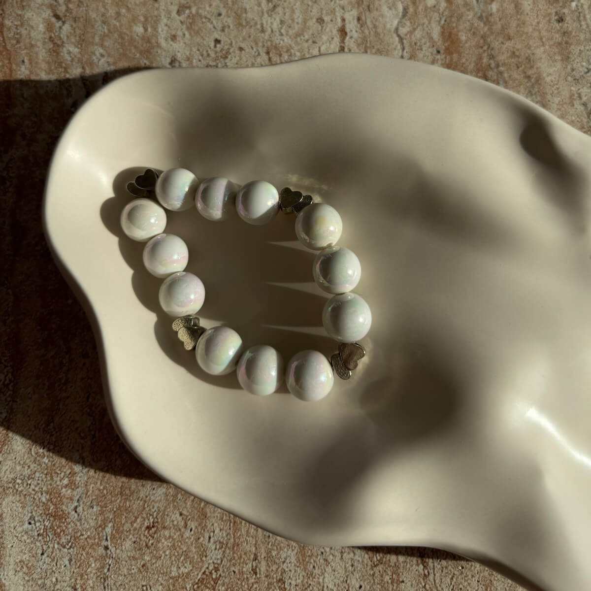 Nahaufnahme des Pearl Whisper Armbands in einer cremefarbenen Schale mit glänzenden Perlen.