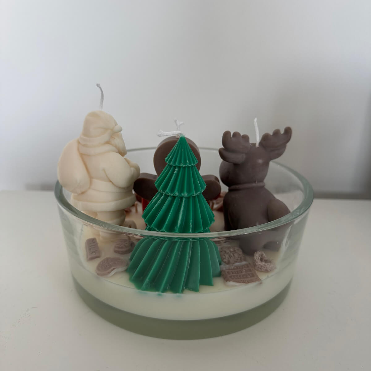 Nahaufnahme der detailreichen Dekoration mit Lebkuchenmann und Elch auf dem weißen Wachs – handgegossen und liebevoll gestaltet.