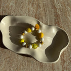 Komplettes Sunny-Sorbet-Armband in einer dekorativen Schale, sommerliche Gelb- und Weißperlen.