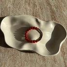 Komplette Ansicht des bronzefarbenen Armbands mit orangen Akzenten in einer hellen Schale.