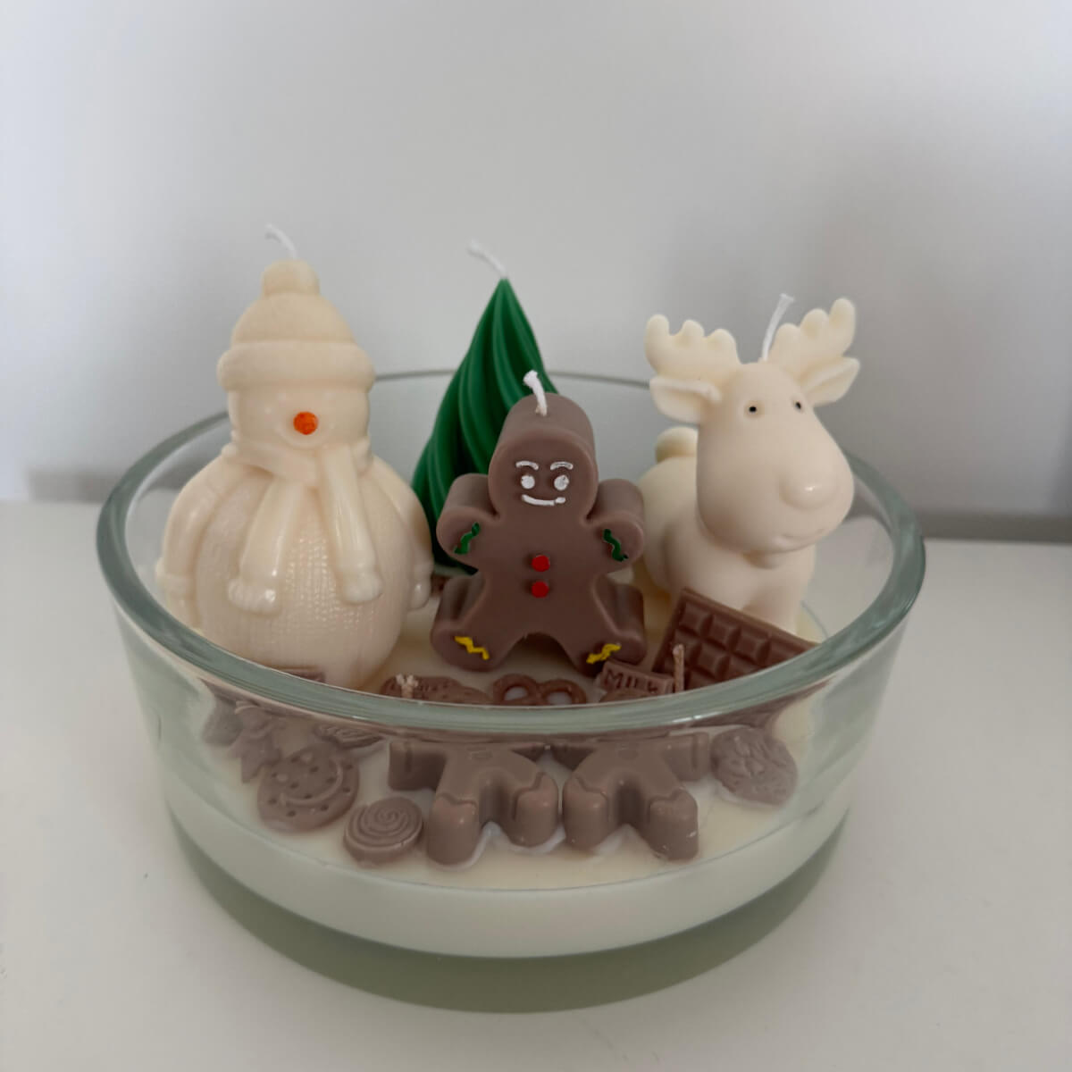 Sweet Winter Wonderland Kerze von der Seite, mit Schneemann, Elch und Lebkuchenmann auf einem schneeweißen Wachsboden.