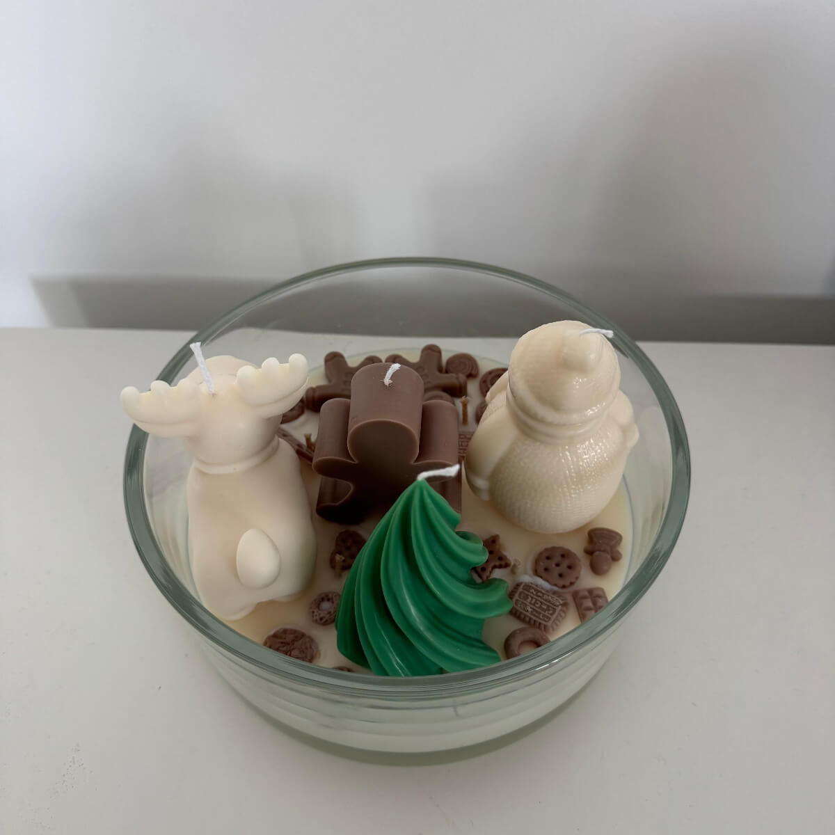 Nahaufnahme des kleinen Schneemanns aus Wachs zwischen Schokolade und Candy-Elementen – Teil der festlichen Weihnachtskerze.