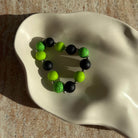 Nahaufnahme des Toxic Orbit Armbands in einer cremefarbenen Schale.