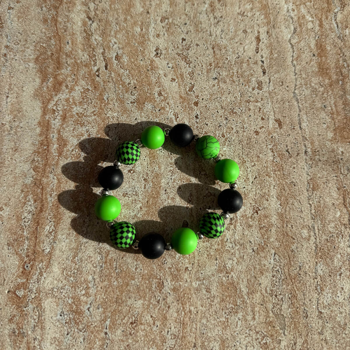 Aesthetic Armband Toxic Orbit mit schwarzen und neon-grünen Perlen auf einem Tisch liegend.