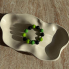 Toxic Orbit Armband komplett in einer Schale arrangiert, neon-grün und schwarz.
