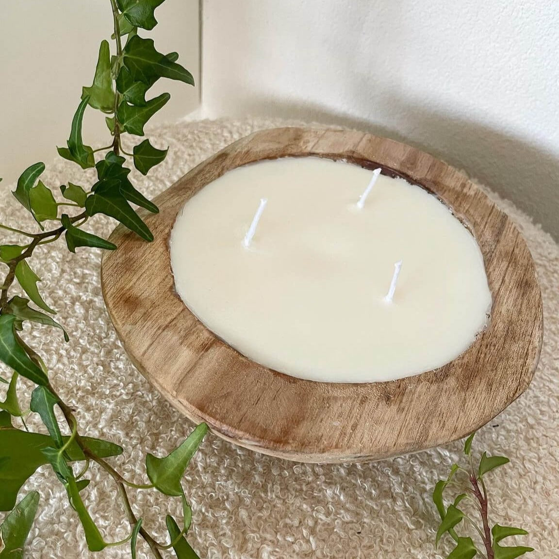 Hier sieht man unsere Woodland Serenity Glow Kerze in einer Holzschale. Sie ist perfekt als Dekoration geeignet. Sie sieht elegant und ästhetisch aus.